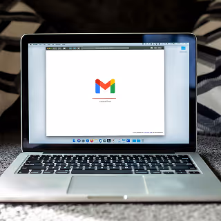 Open laptop on a bed showing the Gmail login screen.