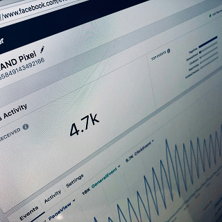 Close-up of a computer screen displaying Facebook analytics, showing 4.7k activity with a graph of engagement trends.