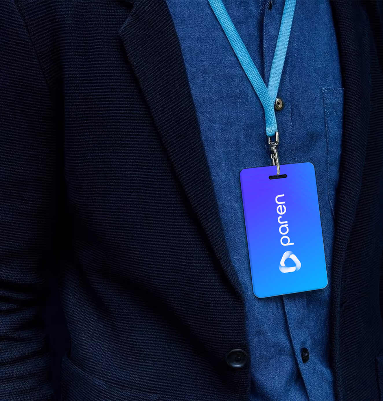Close-up of a person wearing a suit and lanyard with a blue Paren ID badge, featuring the brand’s logo and gradient background.