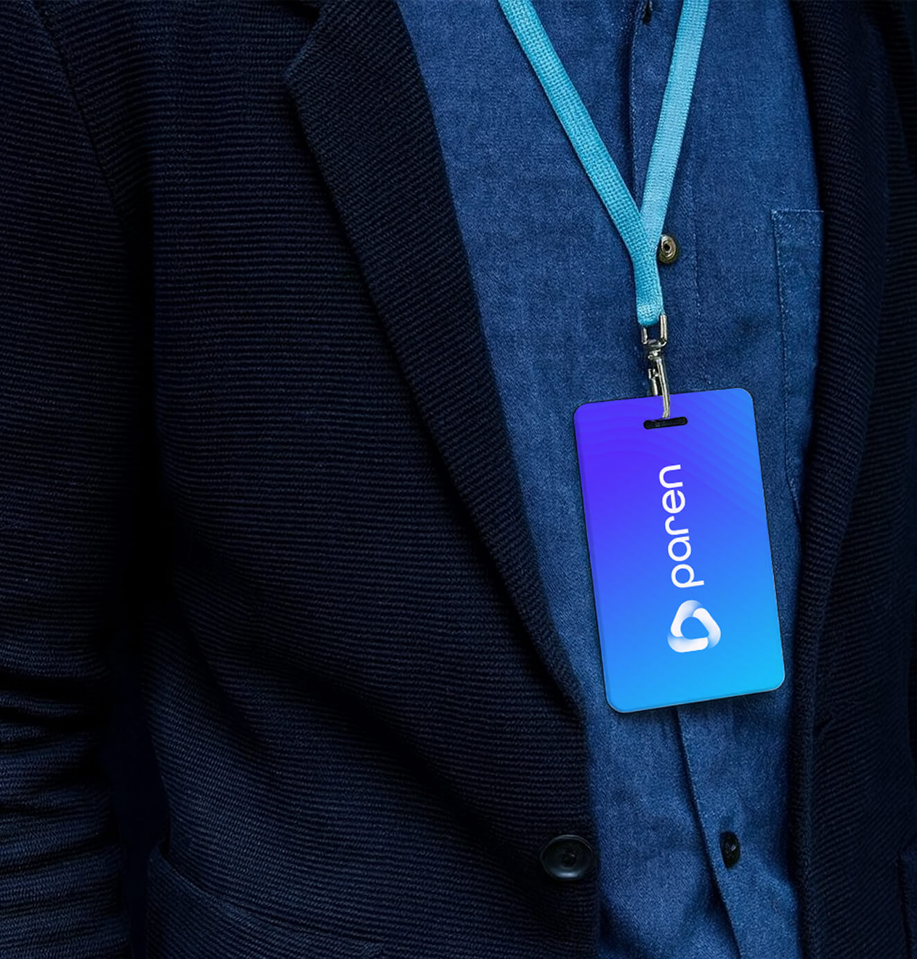 Close-up of a person wearing a suit and lanyard with a blue Paren ID badge, featuring the brand’s logo and gradient background.