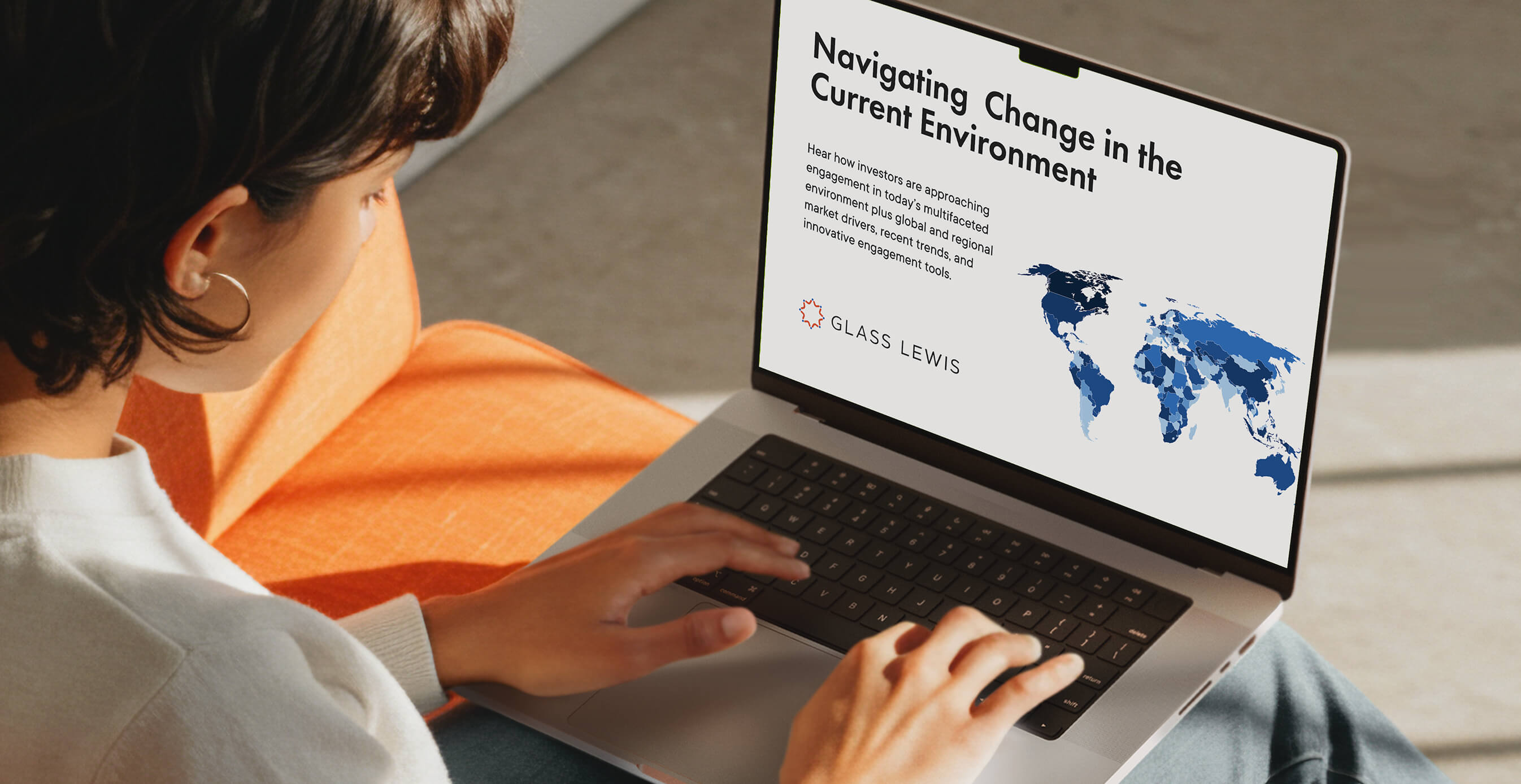 A person types on a laptop displaying a Glass Lewis presentation slide titled ‘Navigating Change in the Current Environment,’ featuring a world map in shades of blue.