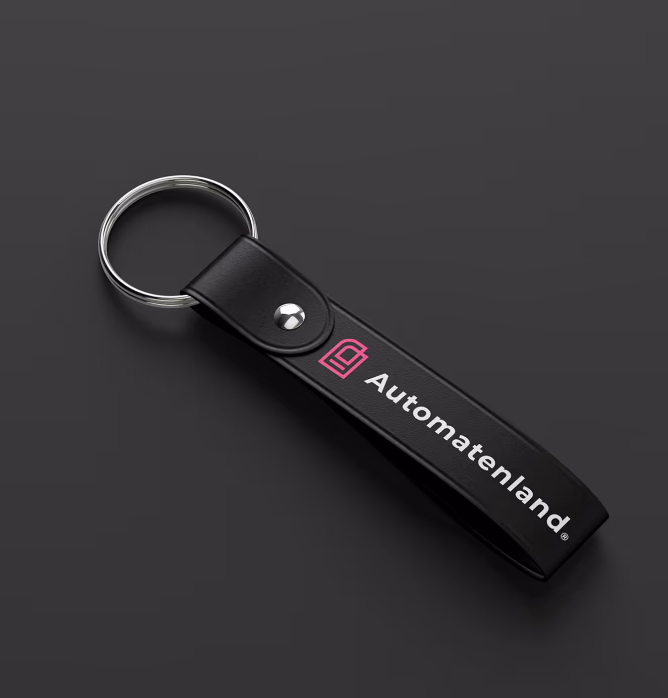 Black leather keychain strap with silver ring, featuring the Automatenland pink logo and white brand name printed on it.
