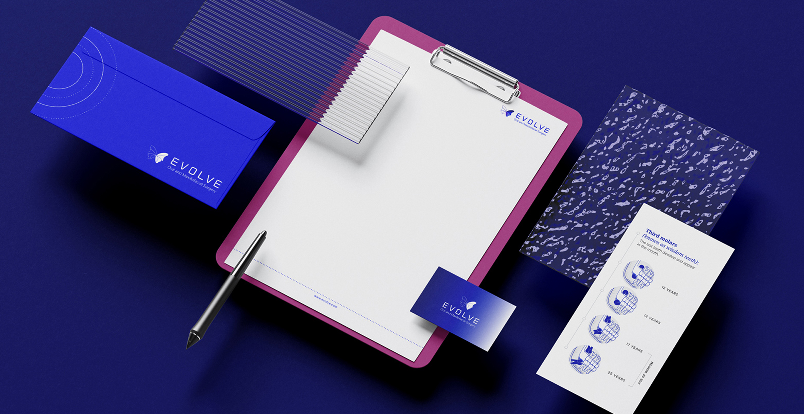Flat lay of Evolve branded stationery including clipboard, pen, business card, and informational pamphlets.