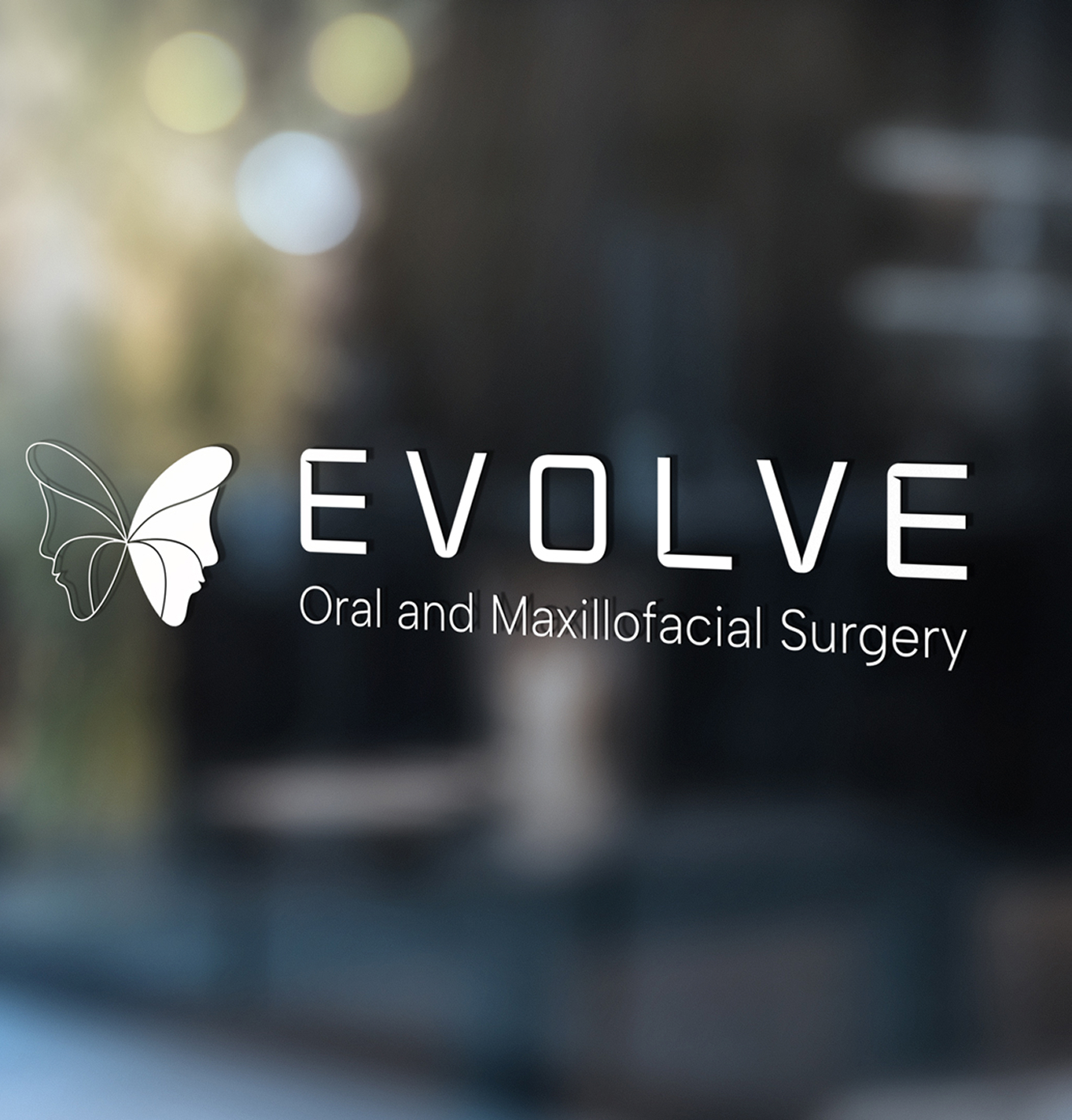 Evolve Oral and Maxillofacial Surgery logo with butterfly icon applied to a glass window in a clinic or office setting.