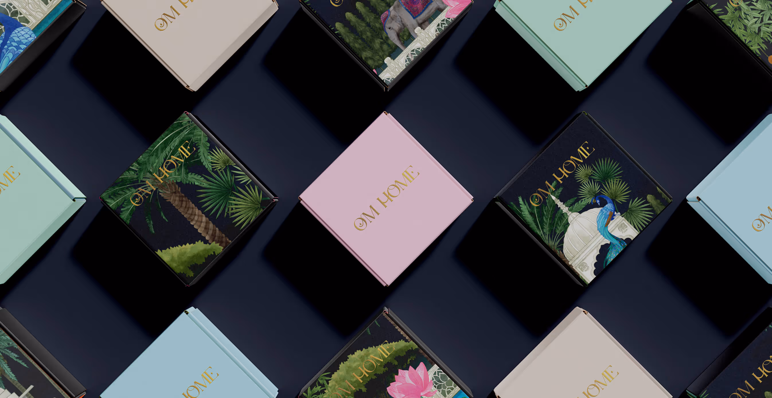 Flat lay of OM Home beauty product packaging in pastel and illustrated boxes, featuring gold lettering and South Asian-inspired designs.