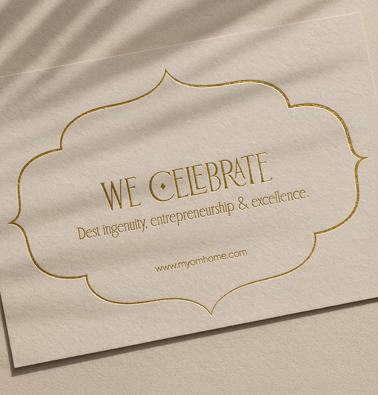 Textured OM Home business card with gold foil lettering reading “We Celebrate Desi ingenuity, entrepreneurship & excellence.”