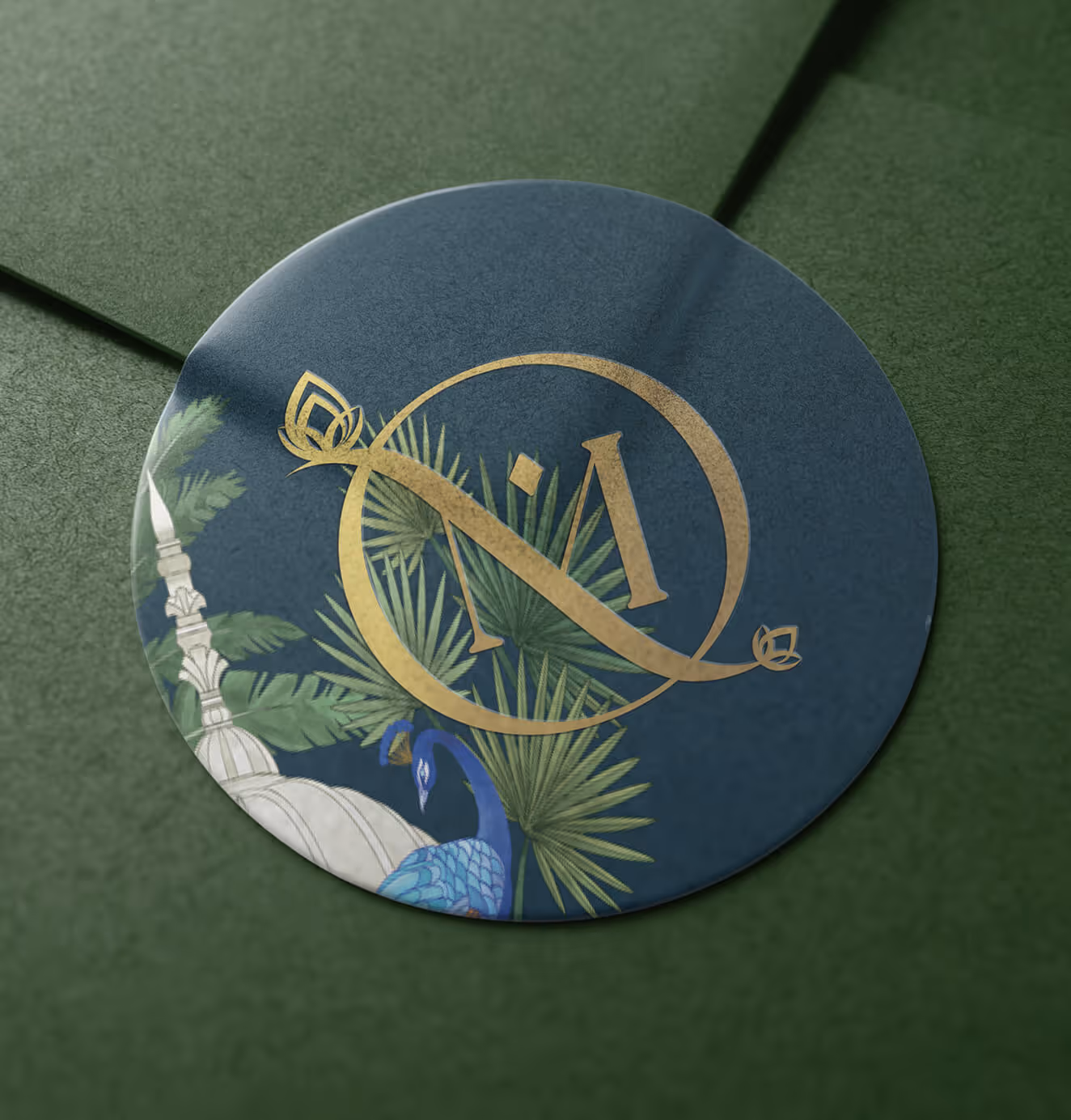 Close-up of OM Home branded circular sticker featuring gold monogram, palm leaves, and a peacock illustration on dark green background.
