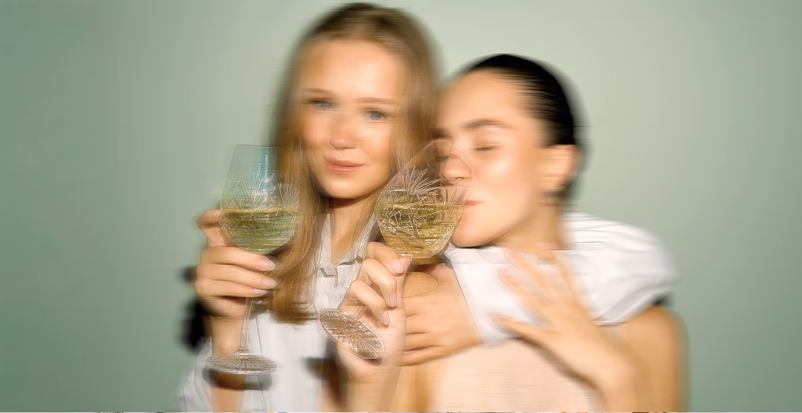 Blurred artistic shot of women holding wine glasses, capturing joy and luxury.