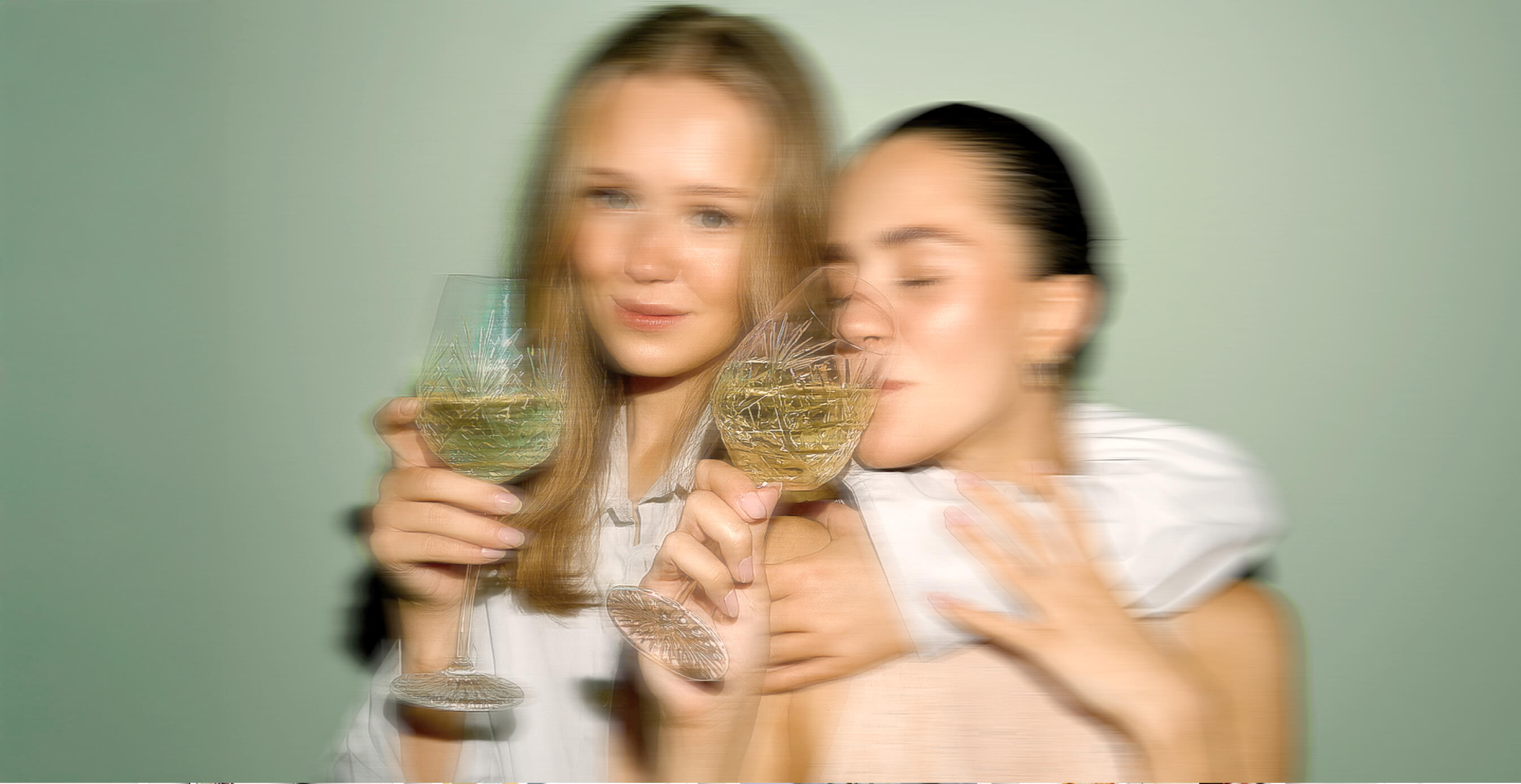 Blurred artistic shot of women holding wine glasses, capturing joy and luxury.