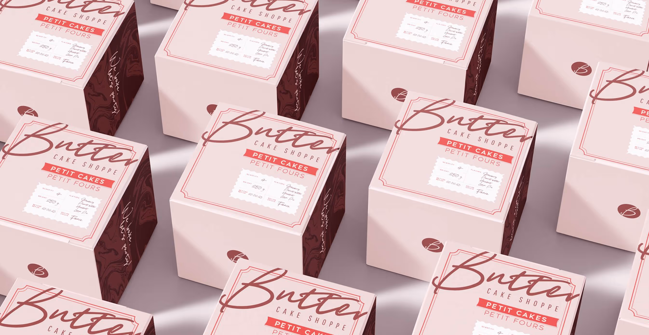 Multiple pink and maroon branded cake boxes with “Butter Cake Shoppe” and “Petit Cakes Petit Fours” labels arranged in a flat lay.