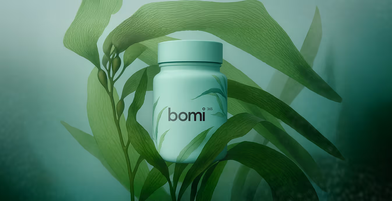 A teal Bomi 365 supplement bottle surrounded by underwater seaweed, evoking freshness and marine origins.