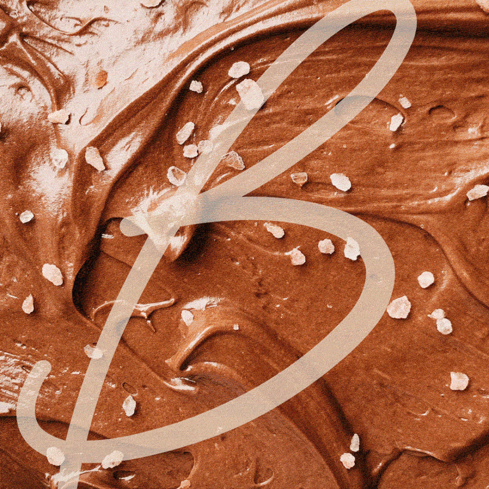 Animated background of rich chocolate swirls with sprinkled sea salt, overlaid by a large scripted “B” from the Butter Cake Shoppe logo.