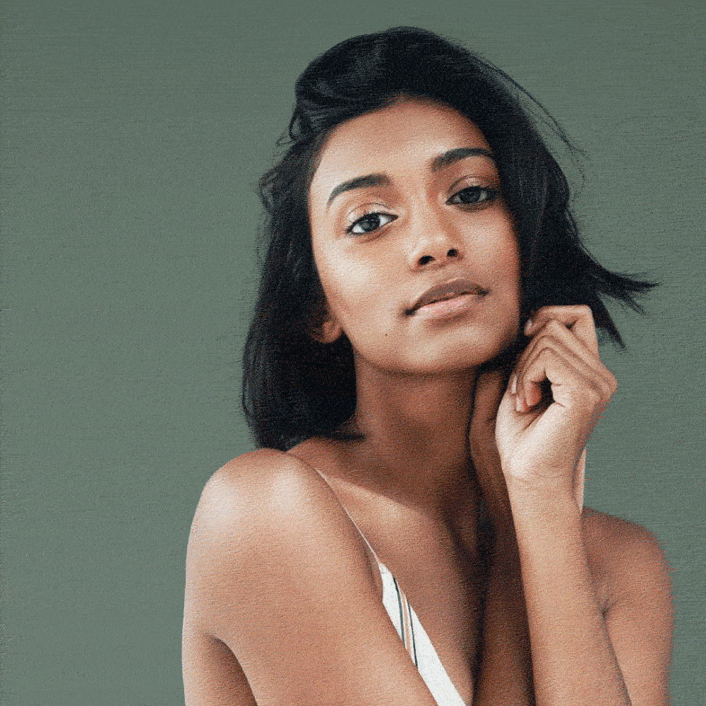 Portrait of a woman with radiant skin and natural makeup against a muted green background, representing OM Home’s modern take on traditional beauty.