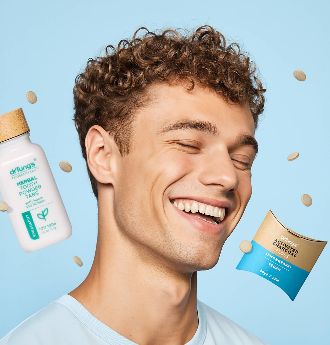 Smiling man with bright teeth on a light blue background, surrounded by floating DrTung’s herbal tooth powder tabs and packaging.