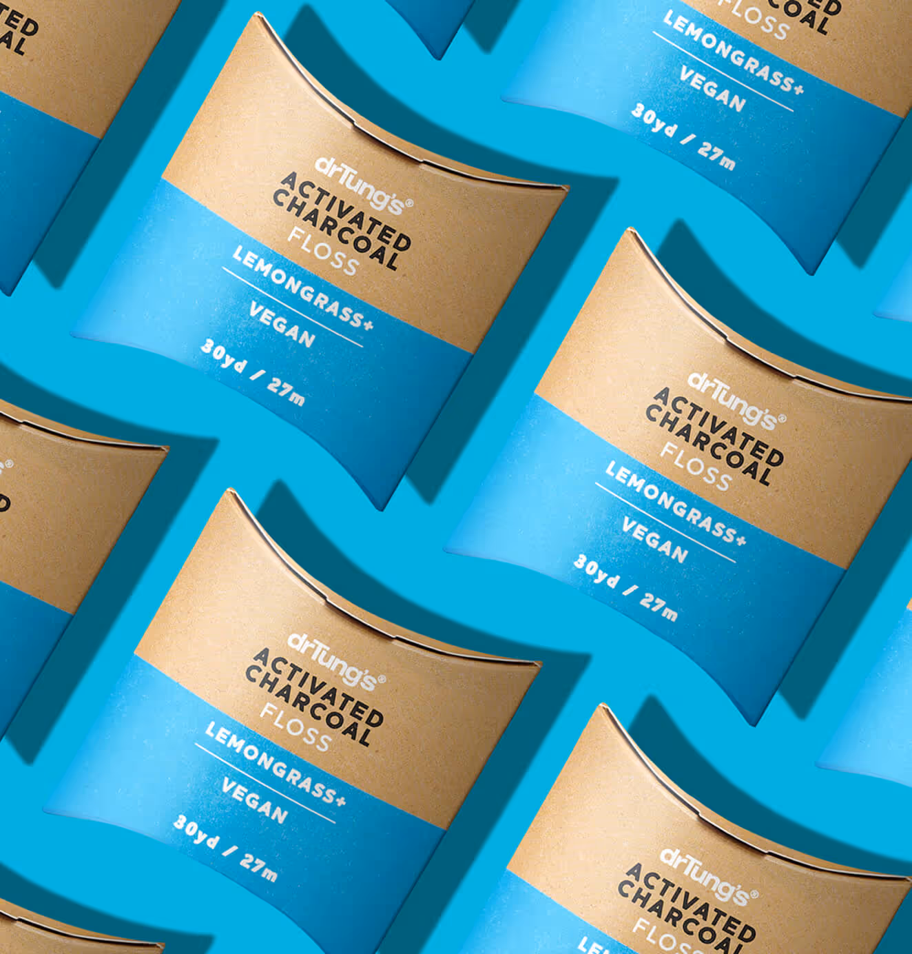 Pattern of DrTung’s Activated Charcoal Floss in brown and blue packaging, arranged diagonally on a bright blue background.