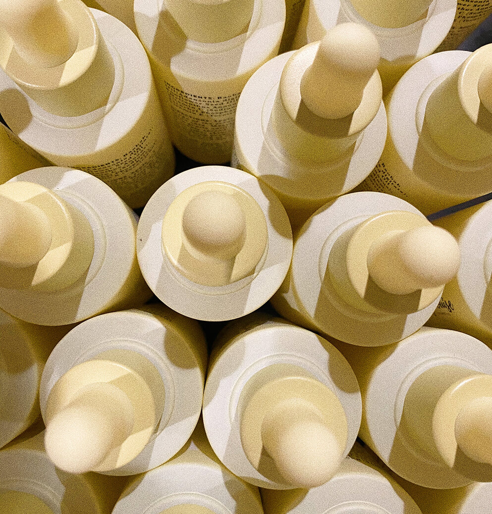 A close-up overhead view of multiple Mary Louise Miracle Serum bottles with yellow dropper caps arranged tightly together.