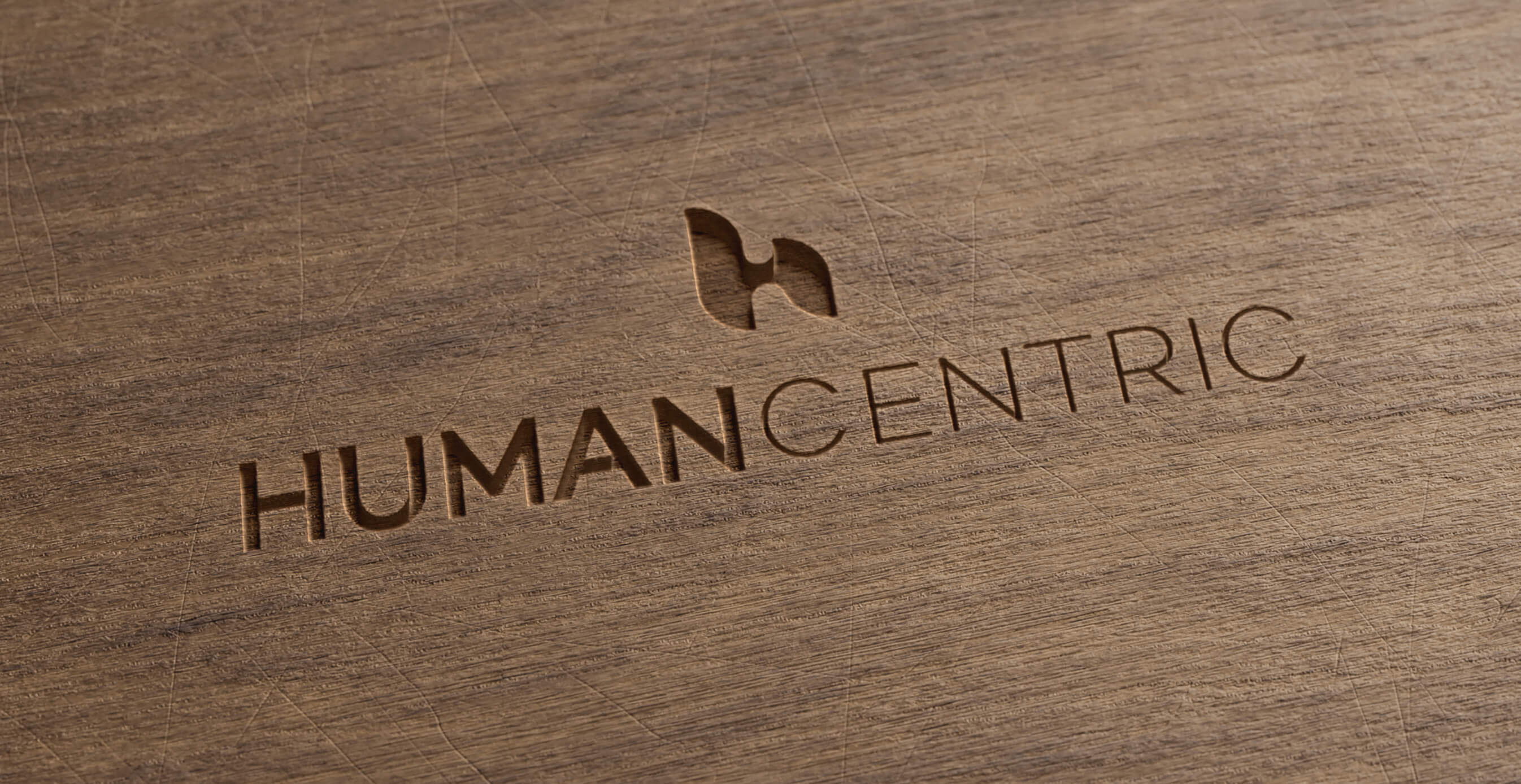 Close-up of the HumanCentric logo engraved into a wood surface, highlighting the brand’s natural and minimal design identity.