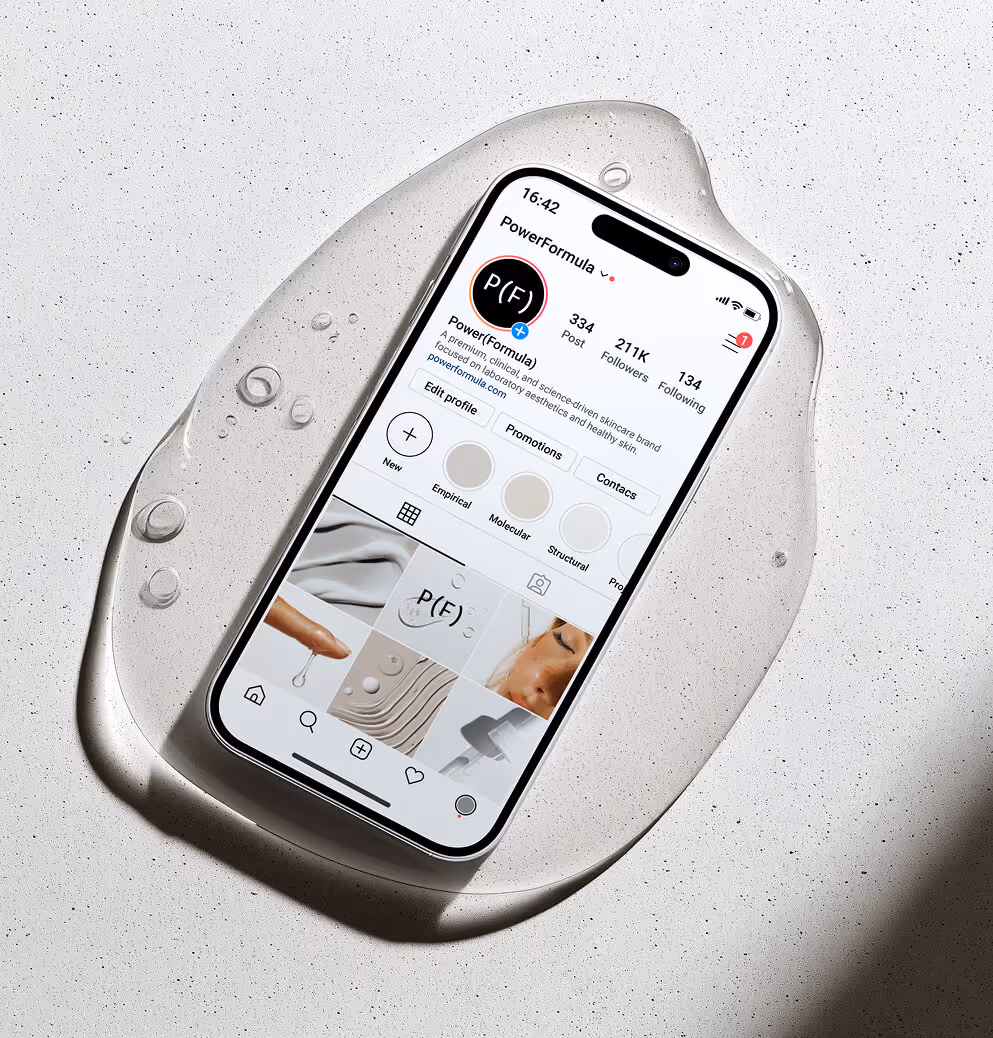 A smartphone displaying the PowerFormula Instagram profile rests on a light textured surface with water droplets, showcasing a clean, modern skincare brand aesthetic.
