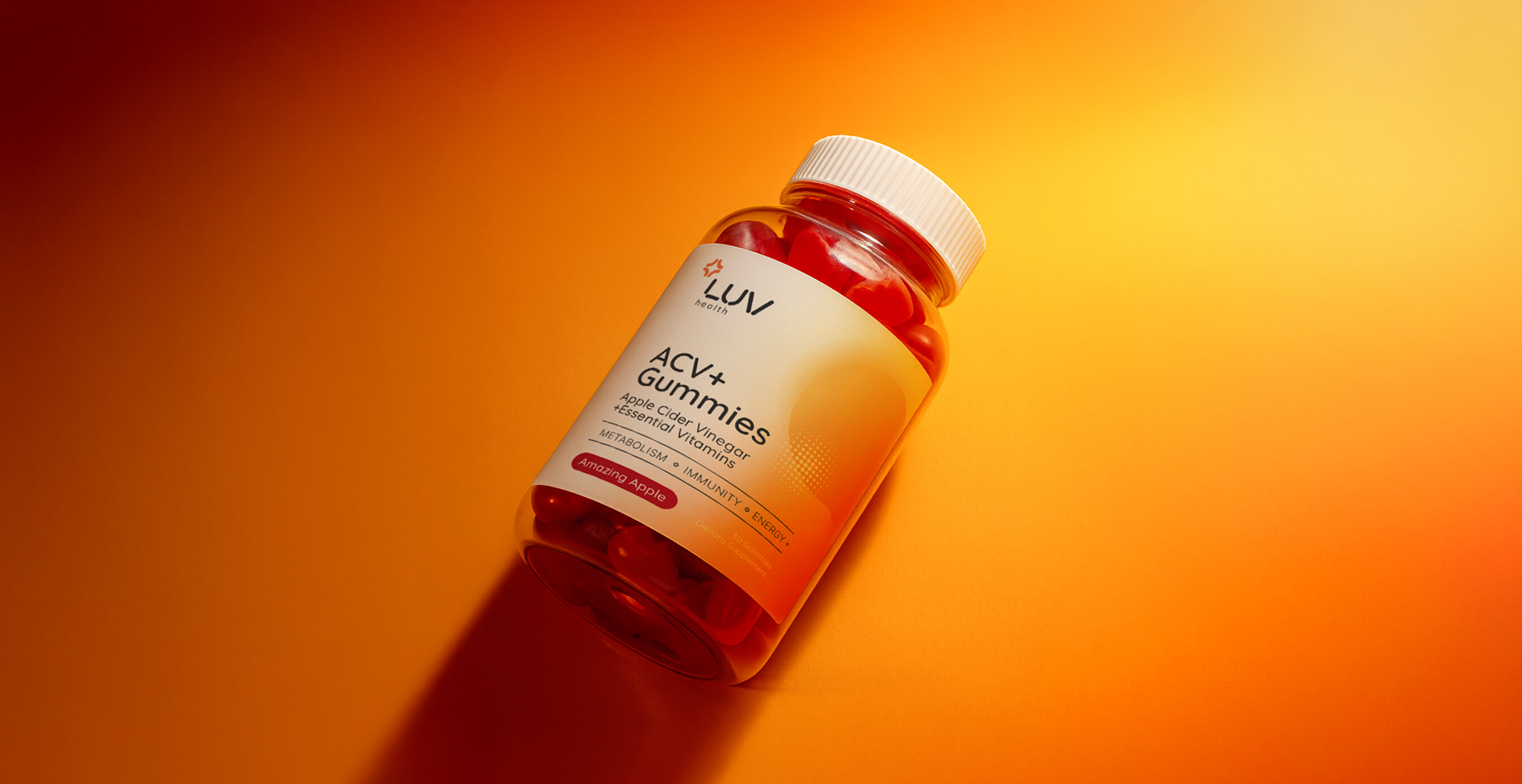 A jar of LUV Health ACV+ Gummies labeled “Apple Cider Vinegar + Essential Vitamins” placed on a vibrant orange-to-yellow gradient background.