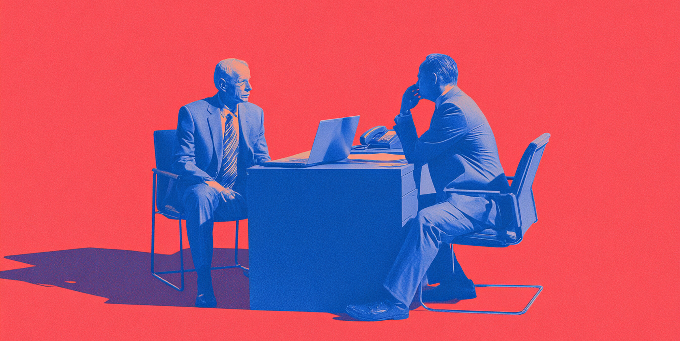 Two professionals in a red and blue setting discussing work at a desk, symbolizing strategic maintenance and client collaboration.
