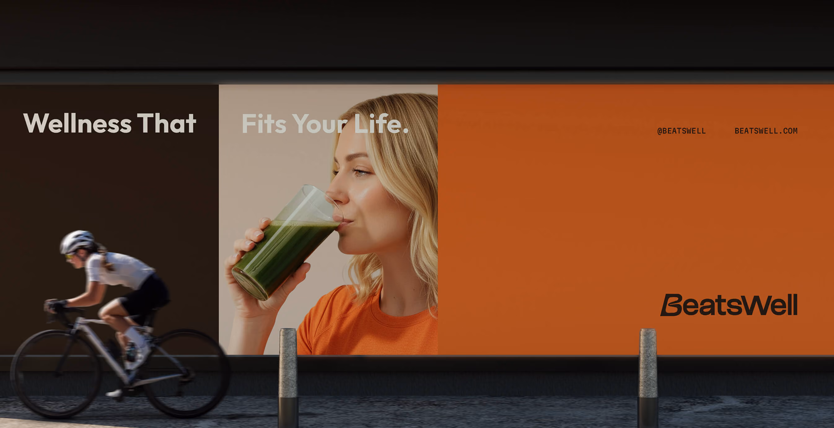 Large outdoor BeatsWell billboard featuring a woman drinking a green smoothie, brand messaging, and logo as a cyclist rides past in the foreground.
