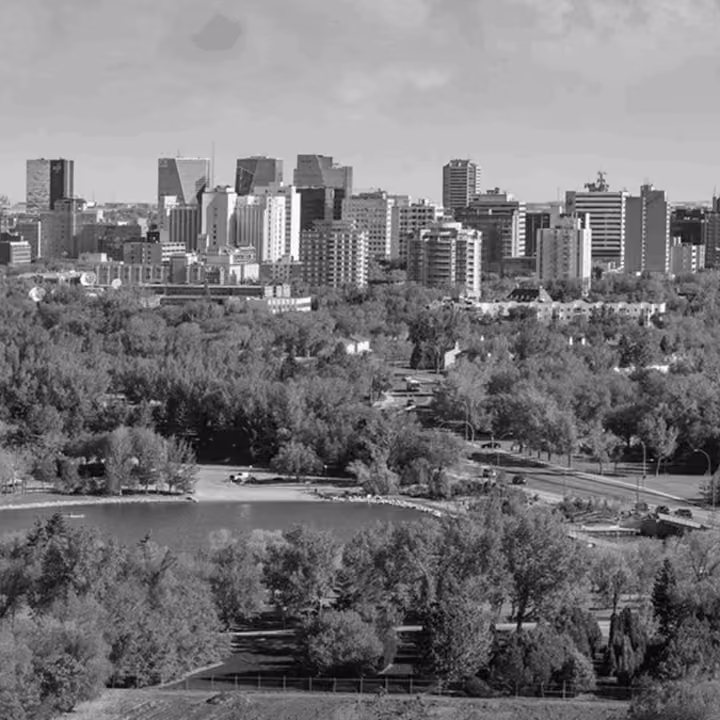 Black and white panoramic view of Regina skyline with residential and commercial buildings overlooking Wascana Park.