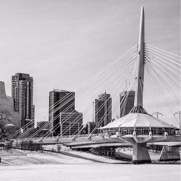 Black and white photo of Winnipeg skyline featuring the Esplanade Riel pedestrian bridge over the Red River in Manitoba.