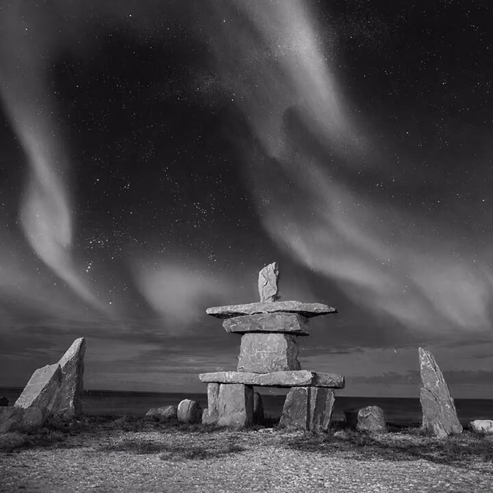 Inukshuk stone monument under a dramatic night sky in Manitoba, symbolizing northern heritage and prairie landscape.