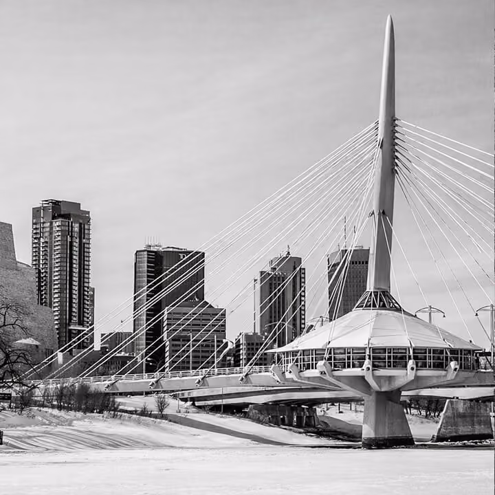 Black and white photo of Winnipeg skyline featuring the Esplanade Riel pedestrian bridge over the Red River.