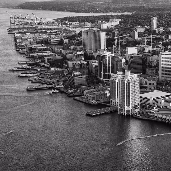 Black and white aerial view of downtown Halifax waterfront featuring harborfront buildings, piers, and shipping cranes in Nova Scotia.