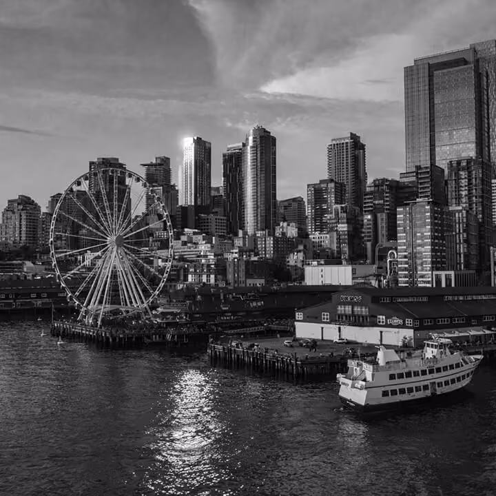 Seattle waterfront view featuring the Great Wheel, pier buildings, and city skyline along Elliott Bay.