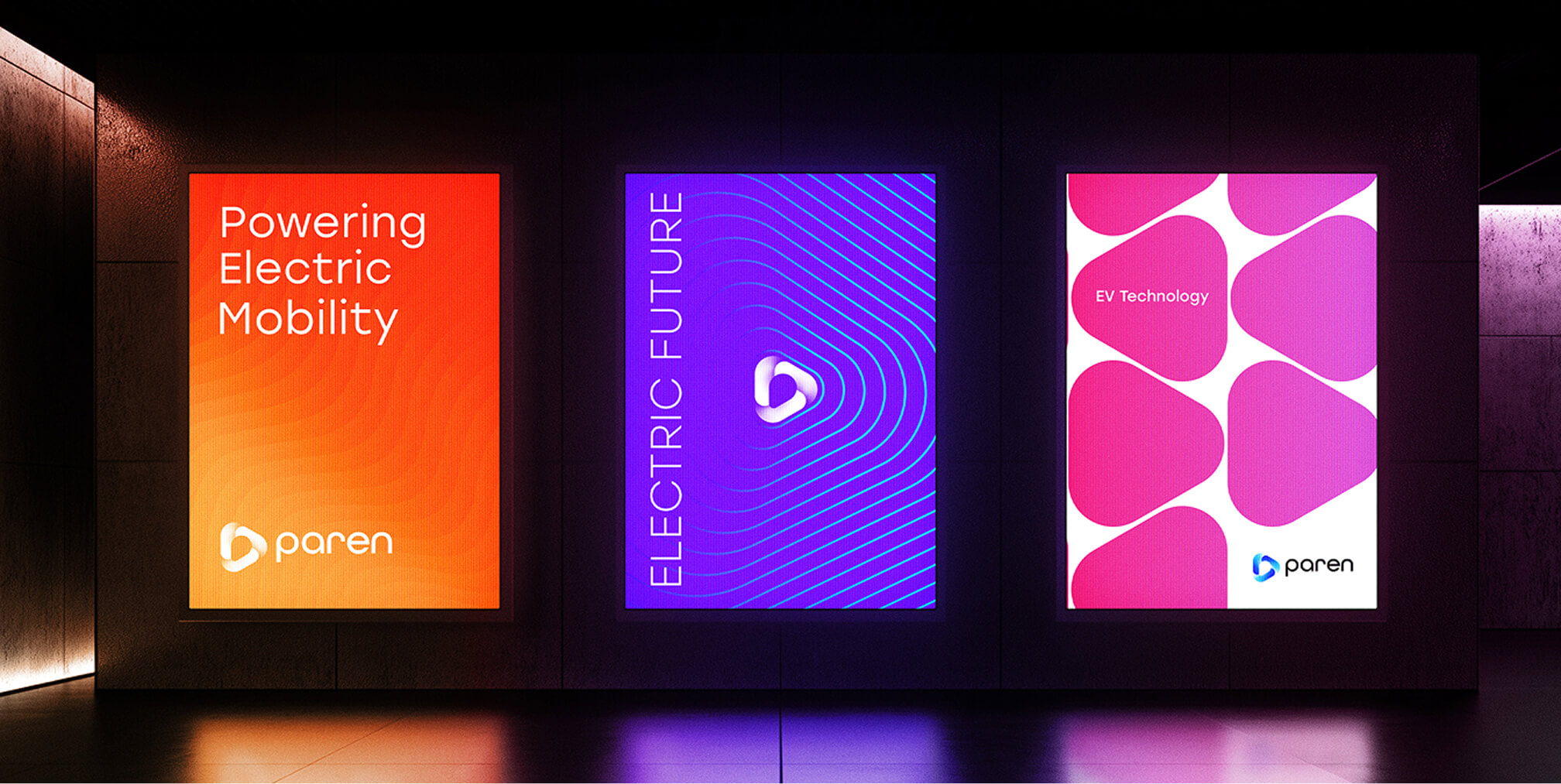 Three illuminated Paren posters on a dark wall reading “Powering Electric Mobility,” “Electric Future,” and “EV Technology.”