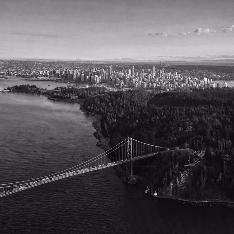 Black and white aerial view of Lions Gate Bridge connecting downtown Vancouver to North Shore across Burrard Inlet.
