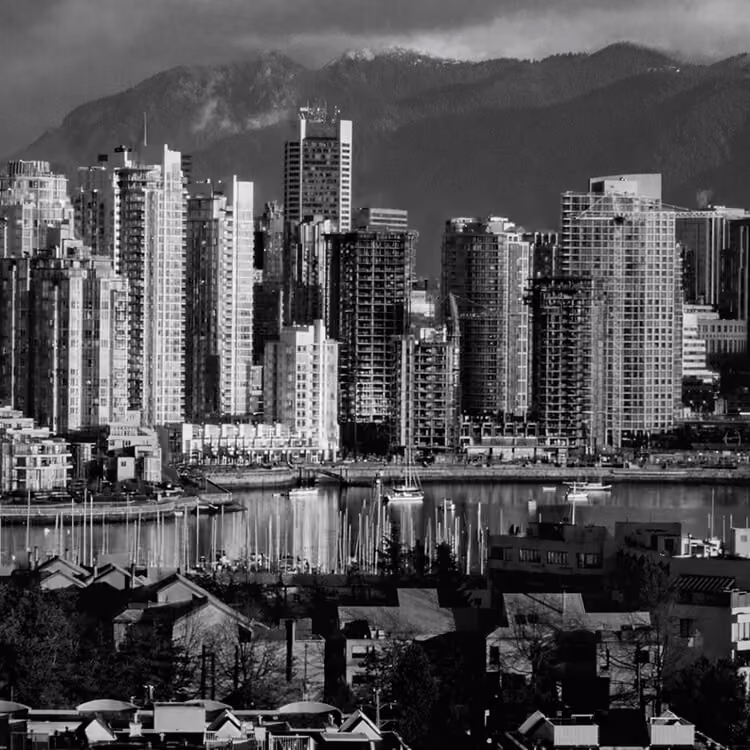 Black and white Vancouver skyline with waterfront marina and North Shore Mountains in the background.