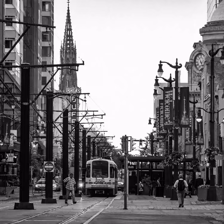 Downtown Buffalo street scene featuring Metro Rail train tracks, Shea’s Theatre sign, and historic architecture.