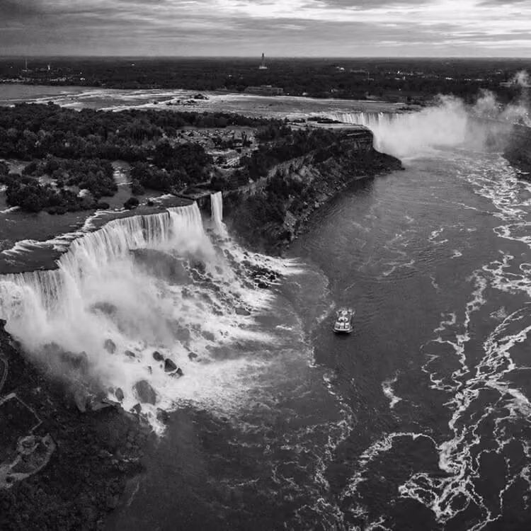 Aerial view of Niagara Falls near Buffalo, New York, with cascading waterfalls and a tour boat below.