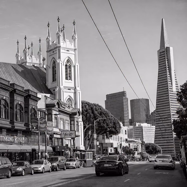 San Francisco street view with historic church and Transamerica Pyramid in the skyline.