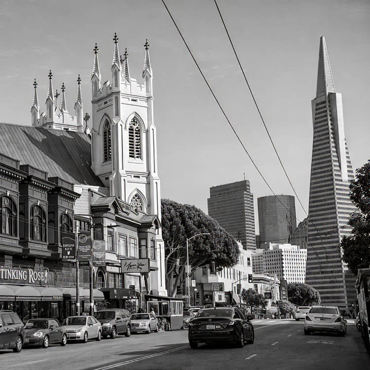 San Francisco street view with historic church and Transamerica Pyramid in the skyline.