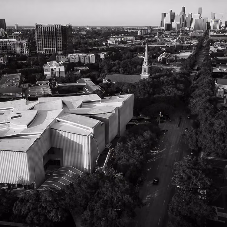 Aerial view of Houston’s Museum District with tree-lined streets and downtown skyline in the distance.