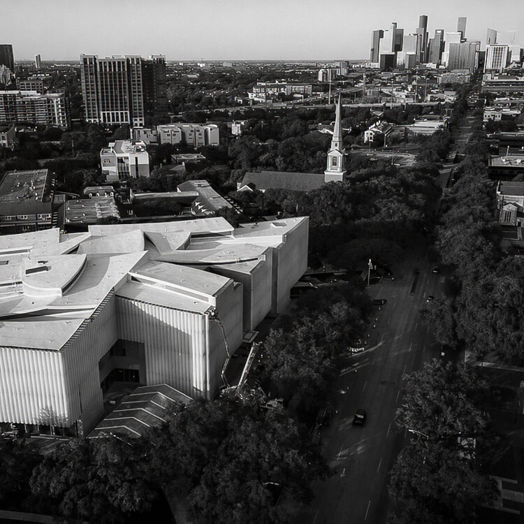 Aerial view of Houston’s Museum District with tree-lined streets and downtown skyline in the distance.