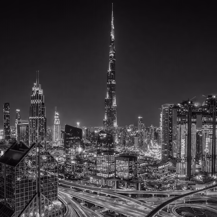 Black and white skyline of Downtown Dubai featuring the illuminated Burj Khalifa and surrounding city lights at night.