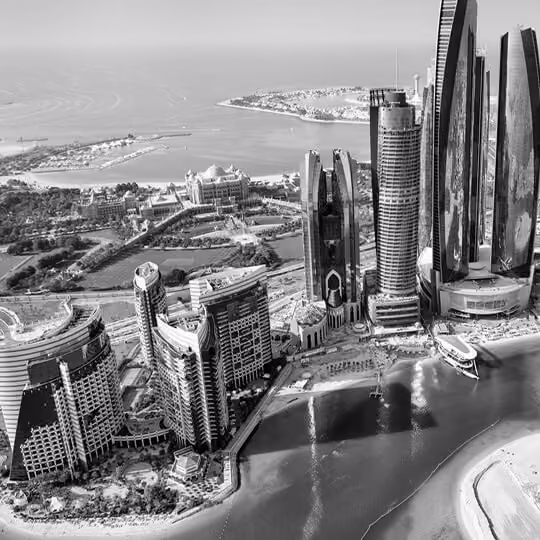 Black and white aerial view of Abu Dhabi’s coastline with modern skyscrapers and waterfront developments.