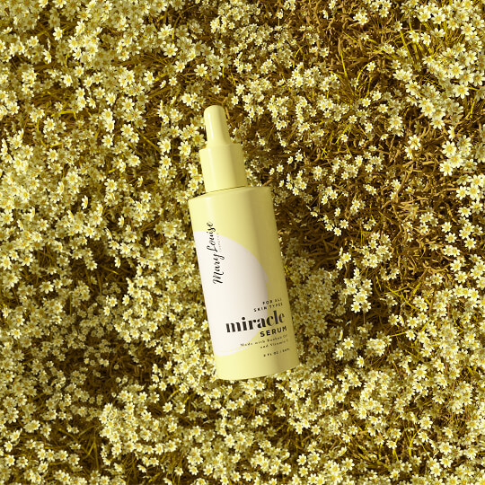 Yellow skincare serum bottle displayed on flowers, highlighting natural beauty product branding design.