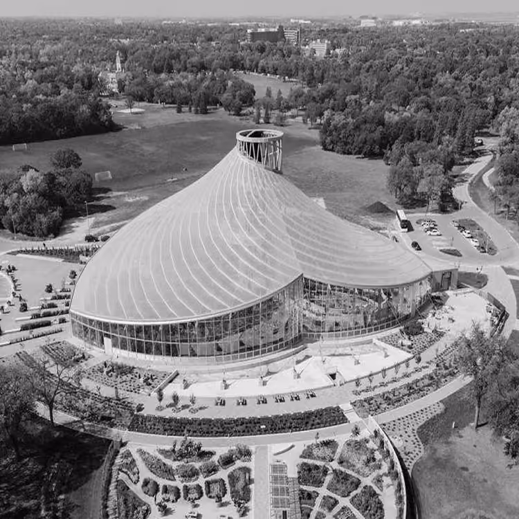 Black and white aerial view of the Leaf at Assiniboine Park, a modern glass conservatory surrounded by greenery in Winnipeg.
