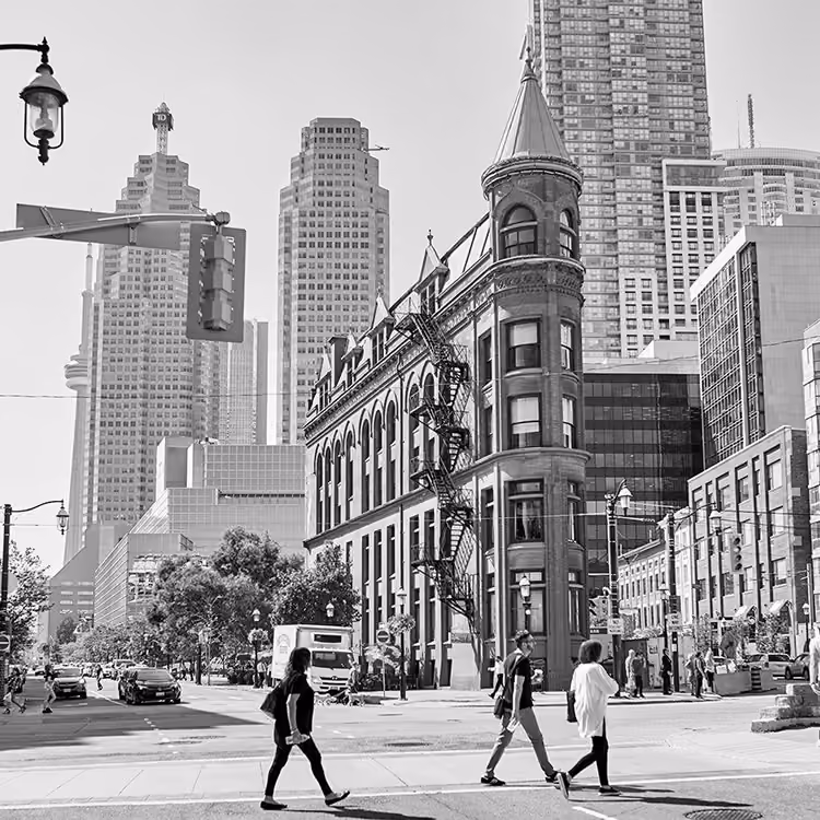 Black and white view of the Gooderham Building (Flatiron Building) with pedestrians walking in downtown Toronto.