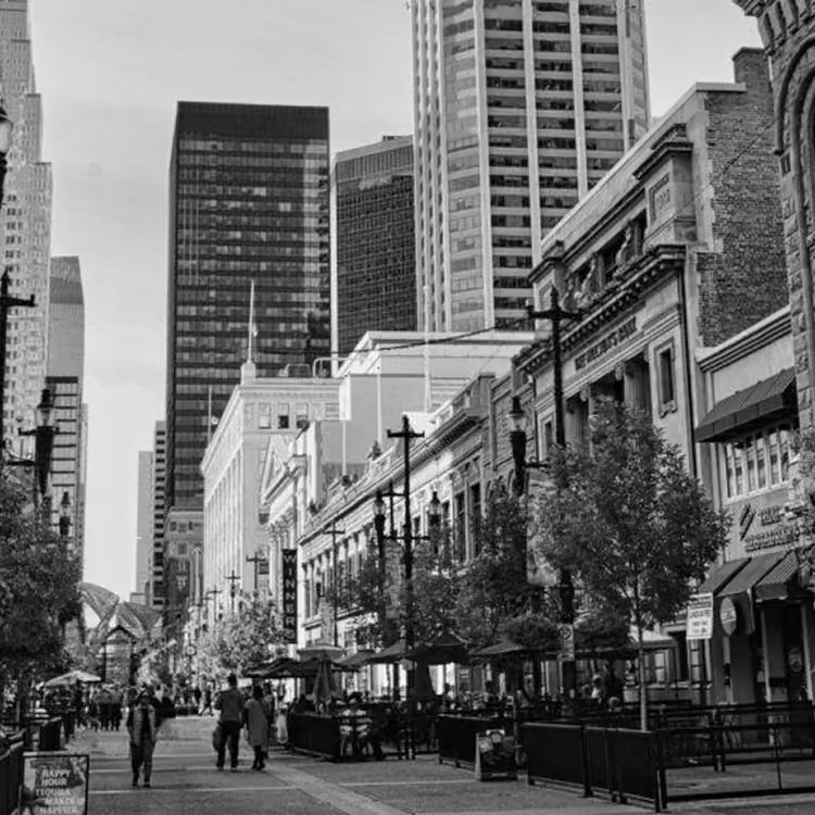 Black and white street scene of Stephen Avenue Walk with pedestrians, restaurants, and historic buildings in downtown Calgary.