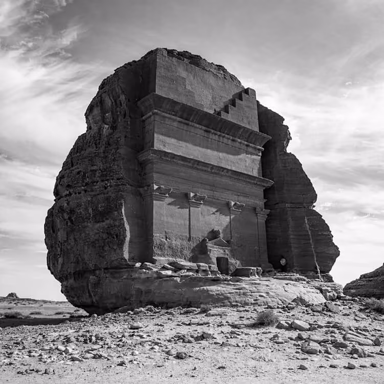 Black and white image of a historic rock-cut monument in the desert landscape of Saudi Arabia.