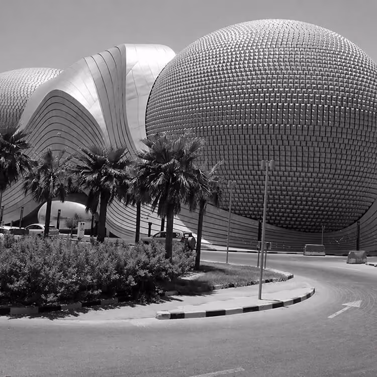 Black and white image of modern spherical architecture and palm-lined streets in Kuwait City.