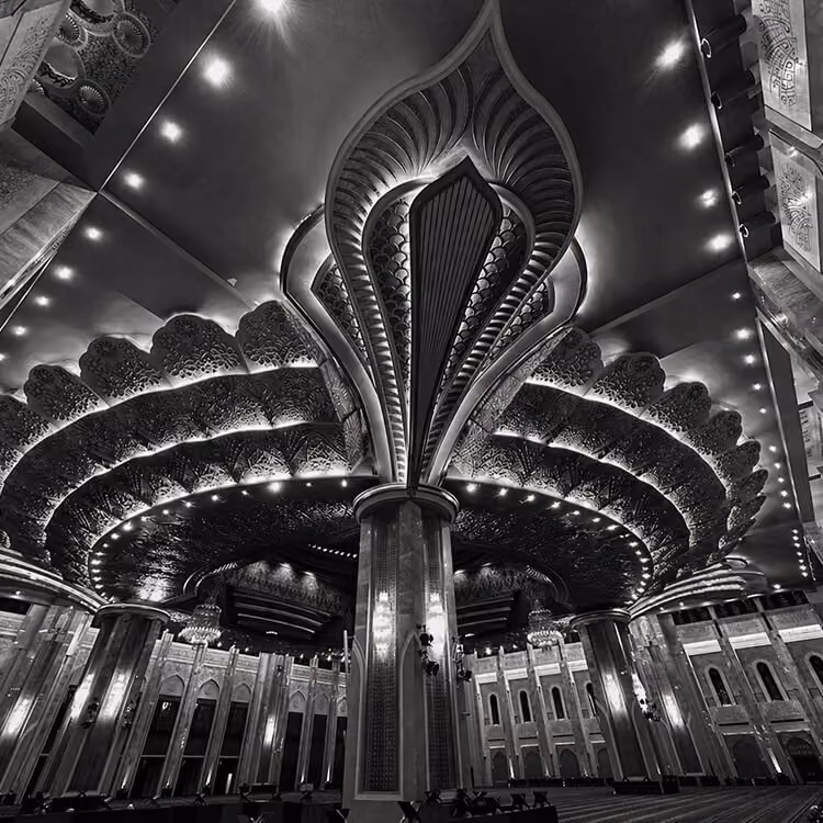 Black and white interior view of the Grand Mosque in Kuwait with ornate ceiling design and intricate architectural details.