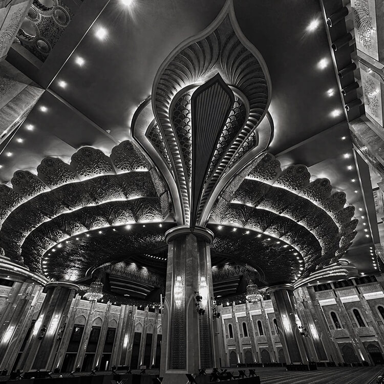 Black and white interior view of the Grand Mosque in Kuwait with ornate ceiling design and intricate architectural details.